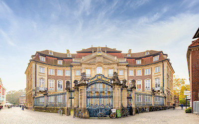 Trotz der engen Lage an der Salzstraße öffnet sich vor dem Erbdrostenhof ein großzügiger Eingangsbereich mit Blick auf die geschwungene Fassade, die Johann Conrad Schlaun geschickt an die Grundstückssituation anpasste.
